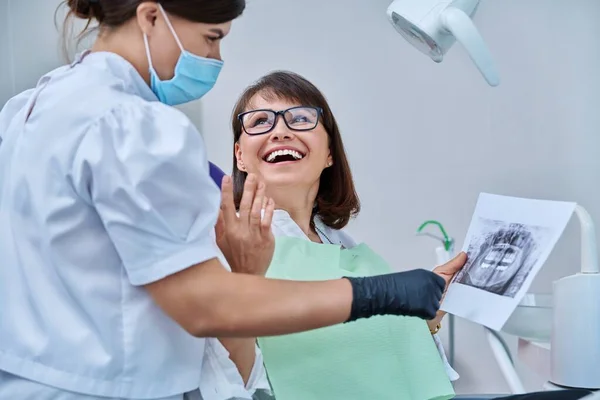 Жінка Лікар Стоматолог Розмовляє Пацієнткою Середнього Віку Стоматологічному Кріслі Обговорюючи — стокове фото