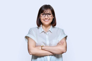 Çekici, kendine güvenen orta yaşlı iş kadını beyaz izole edilmiş arka planda kameraya bakıyor. Kırklı yaşlarda gözlüklü, kollarını çapraz yapmış bir kadın. Yaşam tarzı, güven, iş dünyası, olgun insanlar.