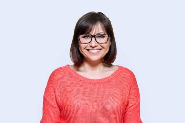 Gülümseyen orta yaşlı bir kadın stüdyonun arka planında kameraya bakıyor. Kırmızı gözlüklü, dişlek gülümsemesi olan neşeli, mutlu, olgun bir kadın. Başarı, neşe, pozitiflik, yaşam tarzı, insanlar