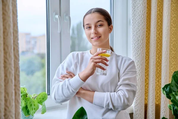 Tonårstjej Med Ett Glas Vatten Med Citron Tittar Kameran Hemma — Stockfoto
