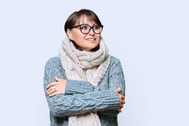 Kış portresi. Güzel olgun bir kadın. Hafif stüdyo arka planında yün örgü elbiseler giyiyor. Çekici orta yaşlı kadın başka tarafa bakıyor. Güzellik, kış mevsimi, soğuk mevsim, 40 'ların insanları konsepti.