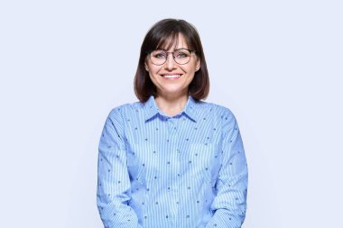 Orta yaşlı, gülümseyen bir iş kadını, beyaz bir geçmişi var. Kameraya bakan 40 'lı yaşlarda olumlu bir bayan. Öğretmen, psikolog, meslek, psikoloji terapisi, başarı, iş, personel konsepti