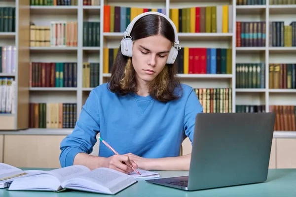 Estudiante Varón Adolescente Estudiando Biblioteca Tipo Con Auriculares Usando Portátil —  Fotos de Stock
