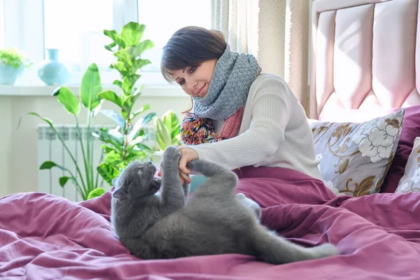 침대에 중년의 여성은 스카프와 뜨거운 음료로 따뜻하게 고양이와 있습니다 아늑하고 — 스톡 사진