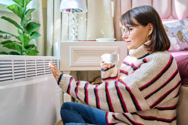 침실에서 스웨터를 여성은 라디에이터 집에서 휴식을 취하며 커피를 가을철 — 스톡 사진