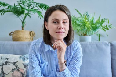 Evdeki kanepede gülümseyen genç bir kadının webcam görüntüsü. Görüntülü konuşma konferansında görüntülü konuşma yapan olumlu bir kadın. Vlog 'u kaydediyor, sosyal medya etkiliyor. Çevrimiçi iletişim, TV teknolojisi