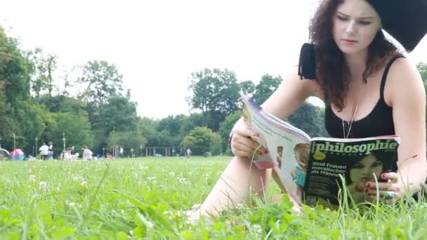 Young university graduate reads at the Park — Stock Video