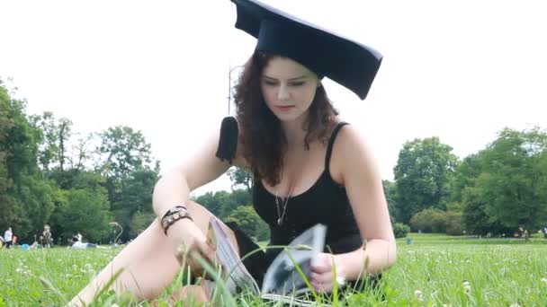Young university graduate reads at the Park — Stock Video