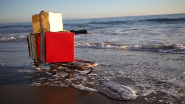 Presentes de Natal em um trenó na praia em Malibu, Los Angeles, nos EUA — Vídeo de Stock