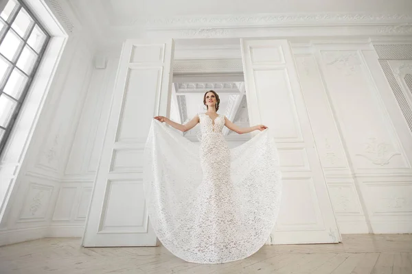 Hermosa novia posando en vestido de novia en un estudio blanco foto. Espejo. Sofá. Bouquet. La puerta. Araña de araña . — Foto de Stock