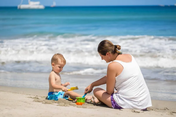 Moeder en zoon bouwen zandkasteel op het strand. — Stockfoto