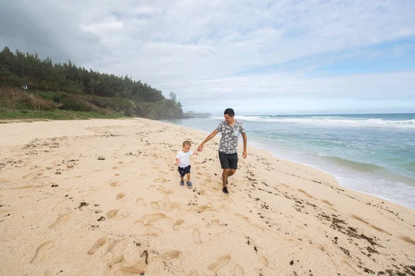 Vader en zoon die hand in hand wandelen op het strand. — Stockfoto