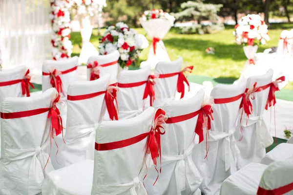 Cerimonia di matrimonio all'aperto. Sedie bianche con nastro rosso — Foto Stock