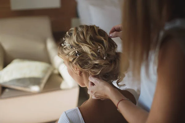 De stylist doet de bruiden haar in het hotel. — Stockfoto