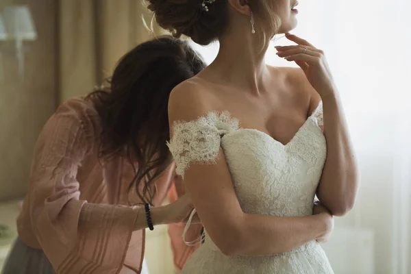 Dama de honor está ayudando a la novia a vestirse . —  Fotos de Stock