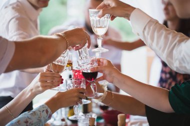 İnsanlar parlak ışıklarla yemek masasında oturup bardakları tıkırdatıyor..