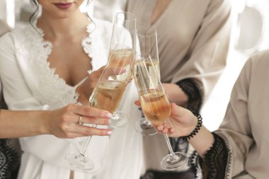 Gelin ve damat şampanya dolu kristal bardaklar taşıyor..