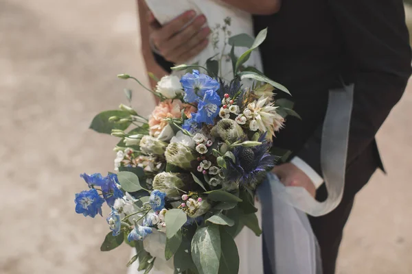 La main du marié serrant le dos de la mariée. Bouquet de mariage au premier plan — Photo