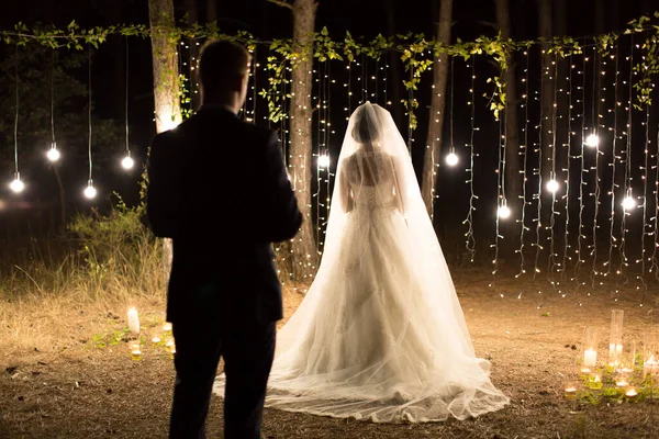 Noite de casamento. Encontro dos recém-casados, a noiva e o noivo na floresta de pinheiros conífera de velas e lâmpadas — Fotografia de Stock