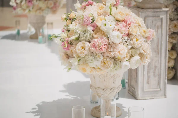 Bellissimo mazzo di rose in un vaso su uno sfondo di un arco nuziale. Bella allestita per la cerimonia nuziale — Foto Stock