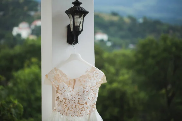 Svatební šaty visí na balkóně na pozadí zasněžených hor. — Stock fotografie