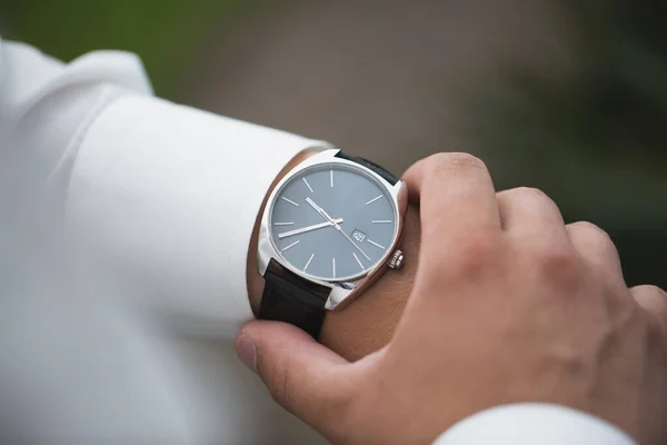 Primer plano del hombre de negocios mirando el reloj en su mano al aire libre, espacio libre. Hombre de camisa blanca comprobando el tiempo de relojes de pulsera de lujo. Cuidado con la mano. preparación de la boda del novio . — Foto de Stock