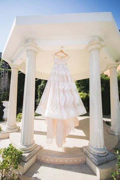 Svatební šaty visí v krásném bílém altánku — Stock fotografie