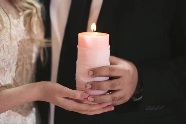 Wedding ceremony, paraphernalia, the bride and groom hold a large candle in their hand. — Stock Photo, Image