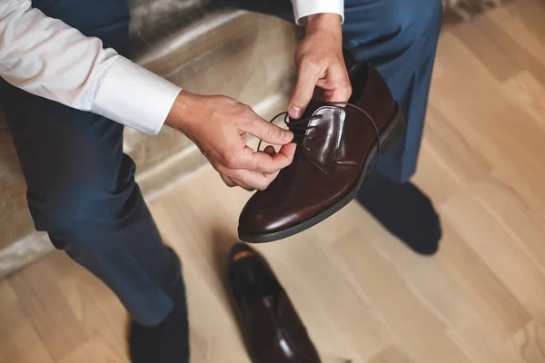 Sposo mettere le scarpe da sposa. Le mani di sposo nuziale che si prepara . — Foto Stock