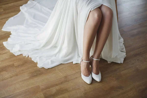 Bruid zet op witte schoenen op voeten. — Stockfoto
