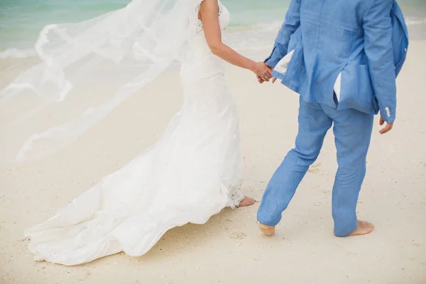 Schöne wunderschöne Braut und stilvoller Bräutigam Händchen haltend, vor dem Hintergrund eines Meeres. — Stockfoto