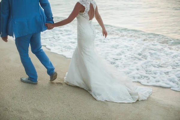 Schöne wunderschöne Braut und stilvoller Bräutigam Händchen haltend, vor dem Hintergrund eines Meeres. — Stockfoto