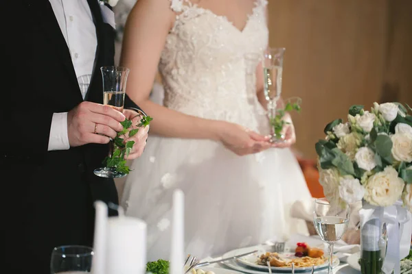 A menyasszony és a vőlegény kristálypoharakat tartanak pezsgővel töltve.. — Stock Fotó