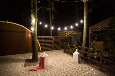 Bahçesi ahşap bir çardağı, ışıkları ve geceleri mumları olan..