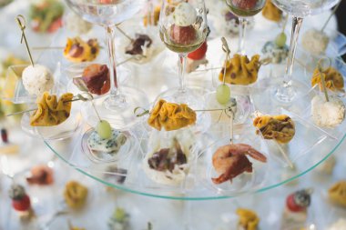 Düğünde resepsiyon. Cam bir masada abur cubur ve şarap bardakları