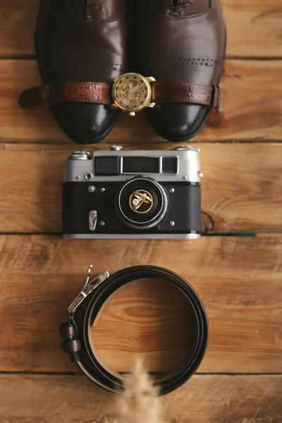 Anelli nuziali su una vecchia macchina fotografica, scarpe, orologio e cintura. Attributi uomo sul pavimento in legno. — Foto Stock