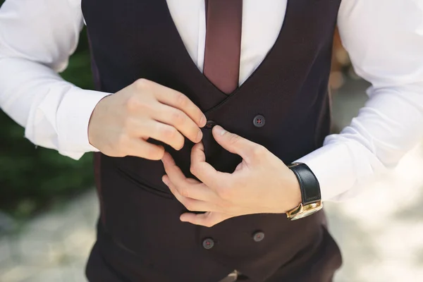 Un hombre se pone un traje de novia y sujeta un botón — Foto de Stock