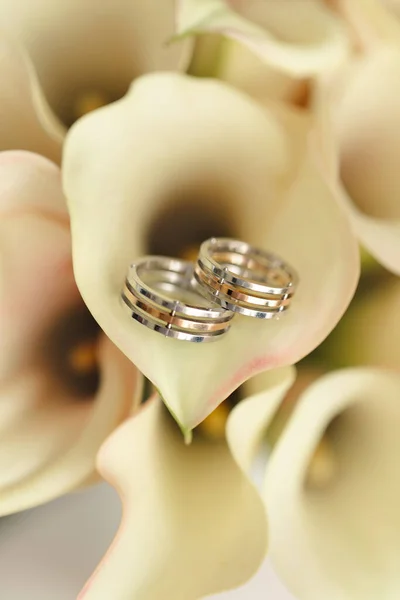Ślubne złote obrączki z bukietem lilii kalla — Zdjęcie stockowe