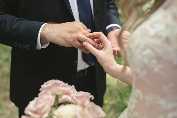 A noiva coloca um anel no dedo do noivo de perto. — Fotografia de Stock