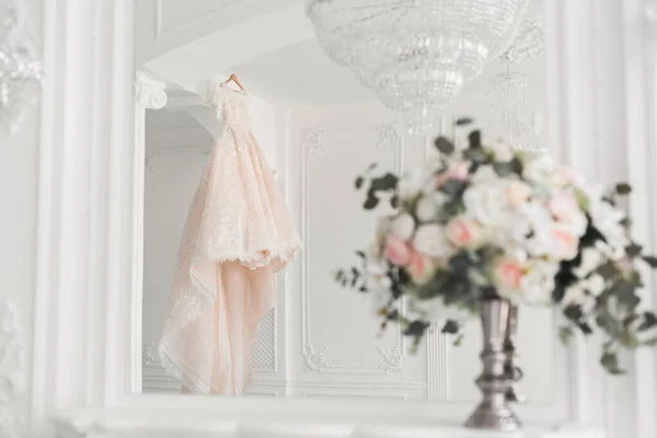 Bruiloft boeket op de achtergrond van een luxe trouwjurk op een hanger. — Stockfoto