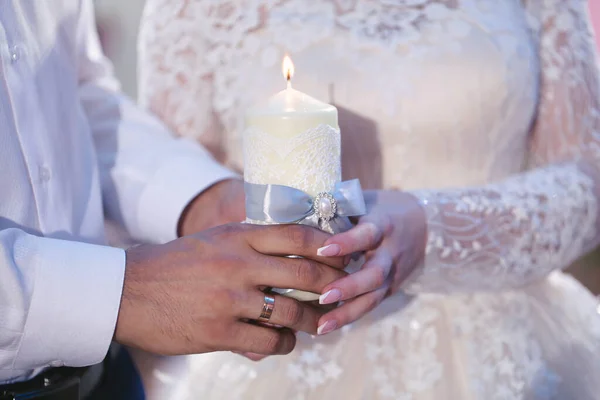 Esküvői szertartás, kellékek, a menyasszony és a vőlegény egy nagy gyertyát tart a kezében.. — Stock Fotó
