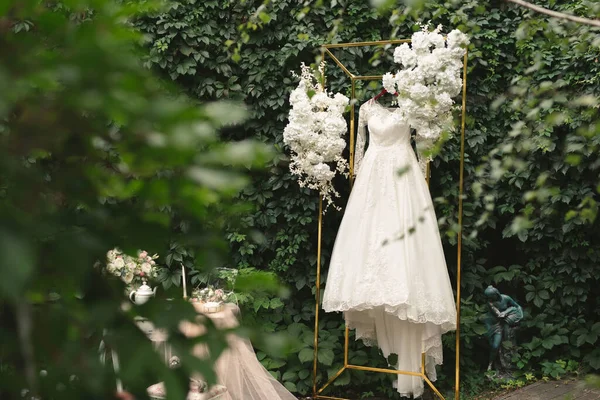 Krásné svatební šaty na ramínku, stůl, květiny, tyl na ulici. Poplatky za nevěstu. Dobré ráno nevěsto.. — Stock fotografie