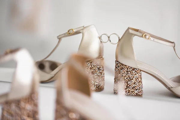 Золотые обручальные кольца между свадебными туфлями невесты. — стоковое фото