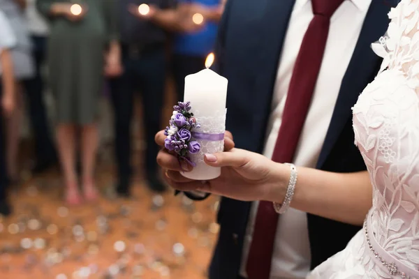 Ceremonia ślubna, akcesoria, panna młoda i pan młody trzymają w ręku dużą świecę. — Zdjęcie stockowe