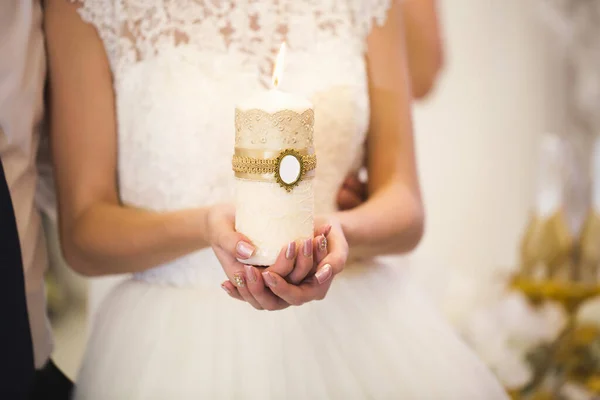 Esküvői szertartás, kellékek, a menyasszony és a vőlegény egy nagy gyertyát tart a kezében.. — Stock Fotó