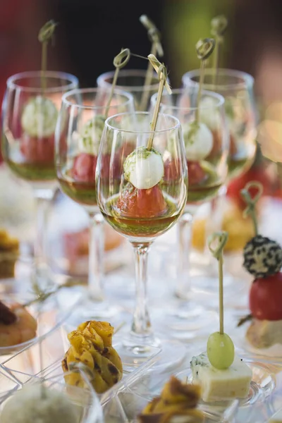 Recepce na svatbě. Svačinky a sklenice na víno na skleněném stole — Stock fotografie