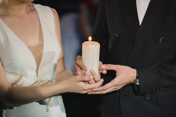 Braut und Bräutigam halten eine Kerze in den Händen. — Stockfoto