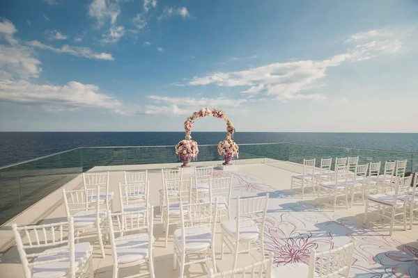Bröllopsbåge med färska blommor på en havsbakgrund. Vaser med färska blommor — Stockfoto