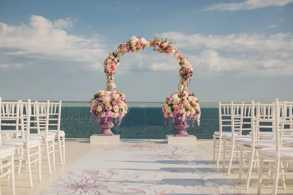 Wedding arch with fresh flowers on a sea background. Vases with fresh flowers — Stock Photo, Image