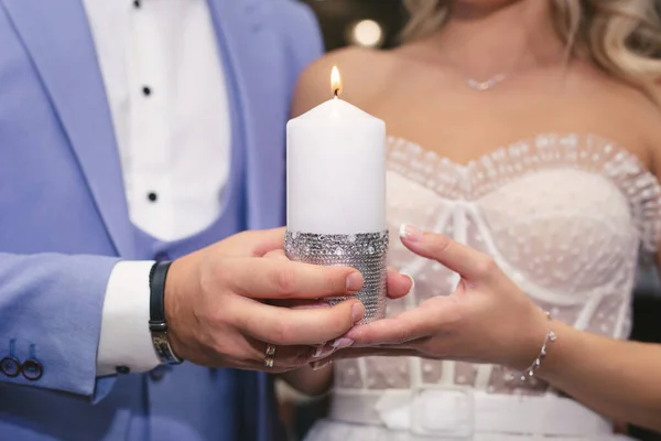 A candle in the hands of the newlyweds. Ignition of the family hearth at the wedding. — Stock Photo, Image